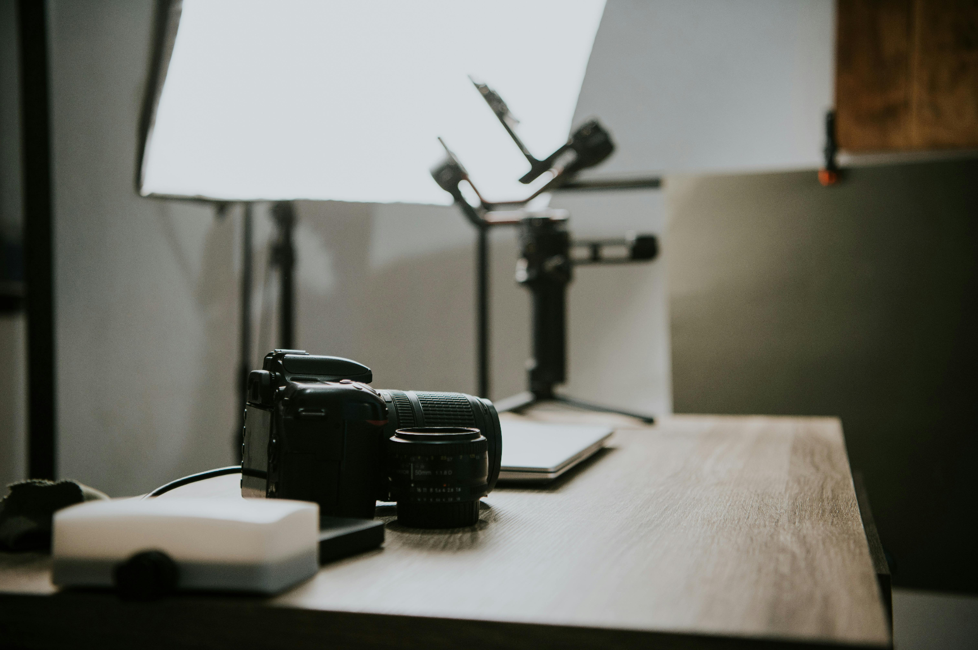 Minimal creative workspace with laptop, notebook and camera lens